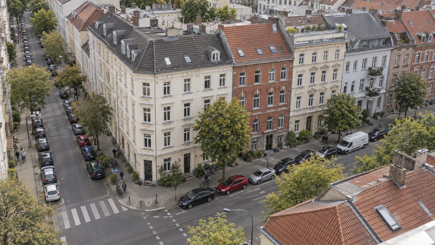 Blick von oben auf ein bewohntes Altbauquartier mit Hauseingängen, geparkten Autos und Straßenbäumen